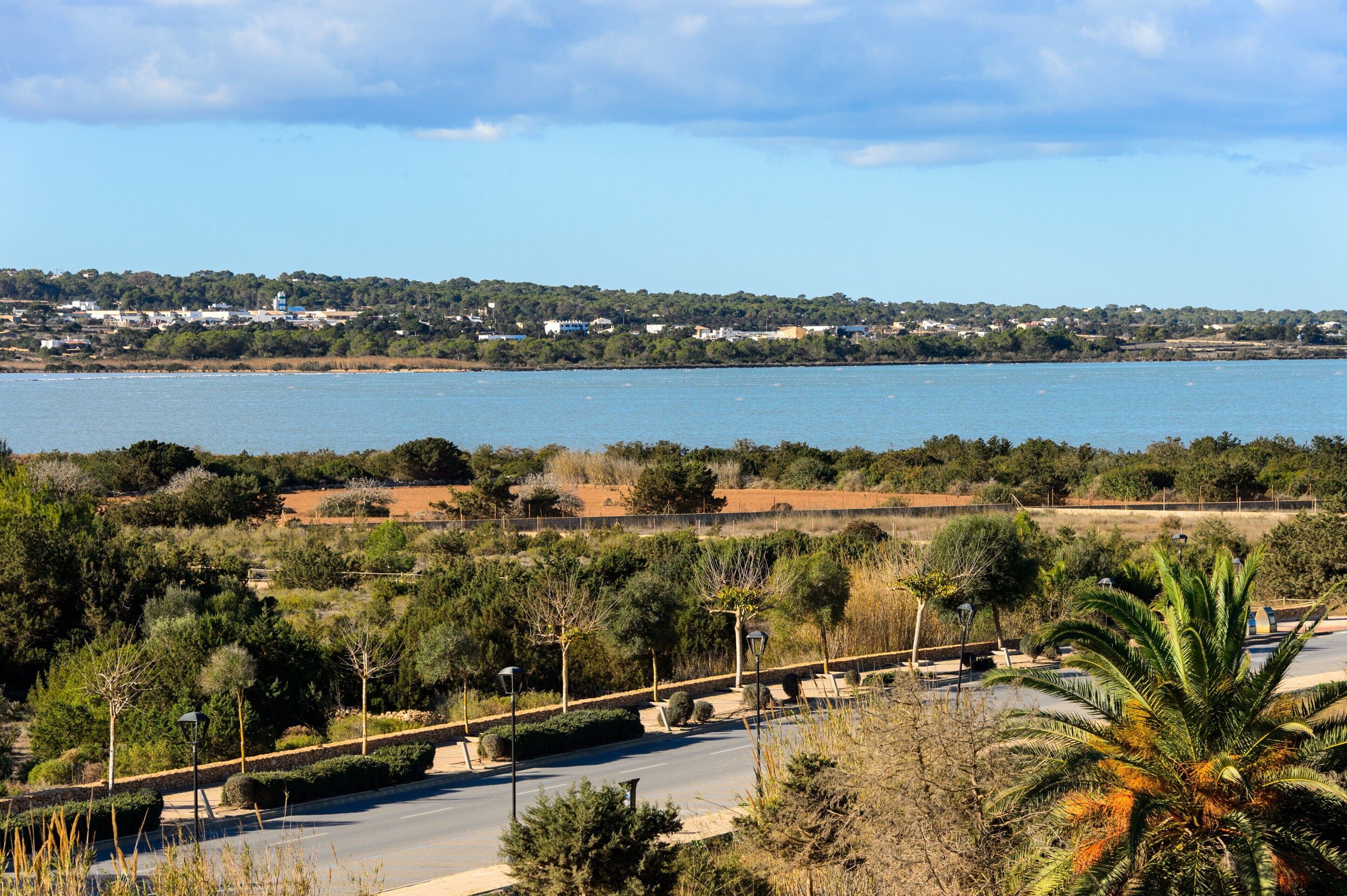 A coastal road with a view of the sea and a distant town.