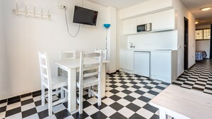 A compact kitchen with white cabinets, a microwave, and a sink. There is a dining table with chairs. The floor has a black and white checkered pattern. - Apartment 'Apartamento Bilo 303' with Lake View, Wi-Fi and Air Conditioning (Es Pujols)