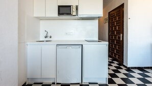 A compact kitchen with white cabinets, a microwave, a dishwasher, and a checkered floor. - Apartment 'Apartamento Bilo 303' with Lake View, Wi-Fi and Air Conditioning (Es Pujols)