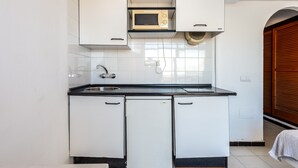 Una cocina con armarios blancos, un microondas, un lavabo y un salpicadero de azulejos.
