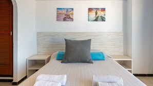 Habitación de hotel con cama, almohadas, toallas y dos cuadros en la pared.