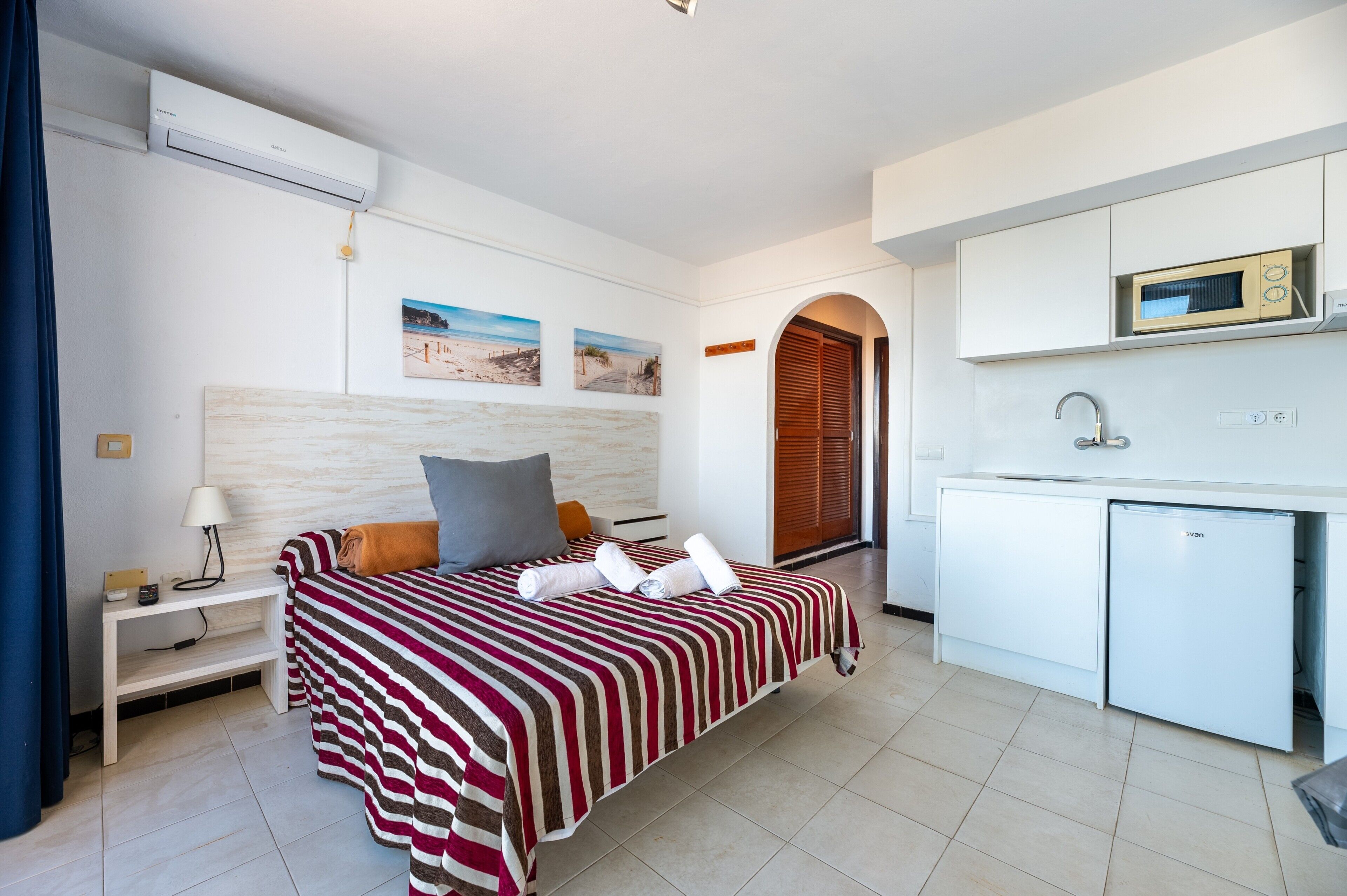 Ein Hotelzimmer mit Bett, Schreibtisch, Mikrowelle und Kühlschrank.