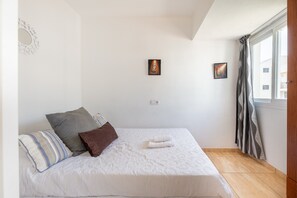 Une chambre à coucher avec un lit, des oreillers, une fenêtre et un tableau accroché au mur.
