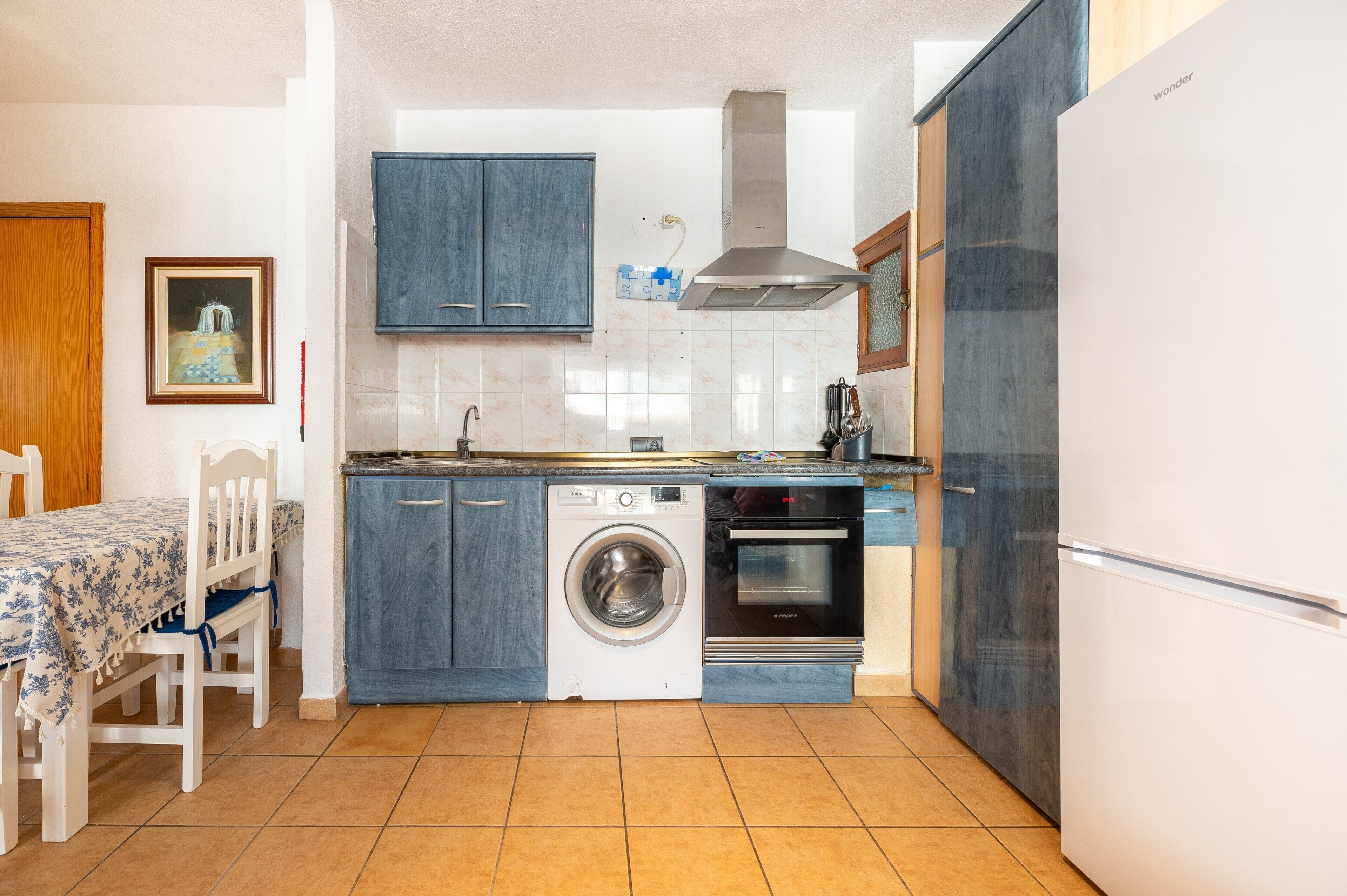 Uma cozinha compacta com máquina de lavar, forno e frigorífico.