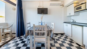 A compact kitchen with a dining area, a flat-screen TV, and a microwave. - Holiday Apartment "Bilo 301" with Private Terrace & Wi-Fi (Es Pujols)