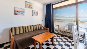 A room with a checkered floor, a sofa, a table, and a balcony with chairs. - Holiday Apartment "Bilo 301" with Private Terrace & Wi-Fi (Es Pujols)