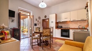 Een moderne keuken met witte kasten, een eethoek met gestreepte stoelen en een gele bank.