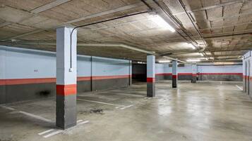 Eine überdachte Parkgarage mit Betonpfeilern, weißen und roten Streifen an den Wänden und einem sauberen, leeren Boden.