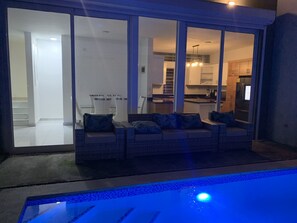 A poolside seating area with a view of the kitchen and dining area. - Villa de Lujo con Picsina Privada a 10 Minutos del Centro de la Ciudad (San Pedro de Macorís)