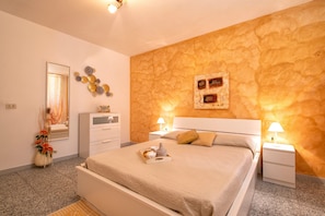Une chambre à coucher comprenant un lit, des tables de chevet, une commode, un miroir et un mur orné d’un motif texturé.