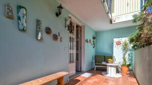 Un balcon avec un banc, une table agrémentée d’un pot de fleurs et des éléments décoratifs sur les murs.