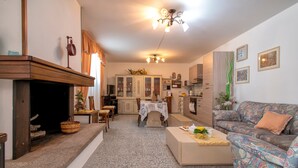 Un salon avec une cheminée, un canapé, une table à manger et, au fond, une cuisine.