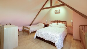 Un dormitorio con dos camas, vigas de madera, una lámpara en el techo y un cuadro en la pared.