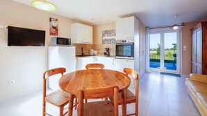 Una cocina moderna con armarios blancos, una mesa de comedor de madera y un televisor montado en la pared.