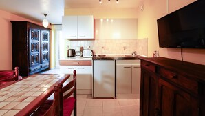 Cocina compacta con una mesa de comedor, un refrigerador, un microondas y un televisor montado en la pared.