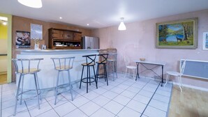 Una cocina con refrigerador, armarios de madera y una barra con taburetes.