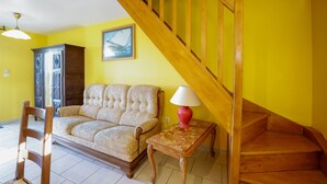 Ein Wohnzimmer mit einer Holztreppe, einem Sofa, einem Tisch mit einer Lampe und einem gerahmten Bild an der Wand.