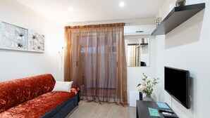 Ein modernes Wohnzimmer mit einem roten Sofa, einem Fernseher, einem Couchtisch mit Fernbedienungen und einer dekorativen Vase.