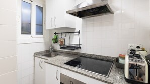 Eine Küche mit weißen Schränken, einer Edelstahl-Dunstabzugshaube, einer doppelten Spüle, einem eingebauten Kochfeld und einem Toaster.