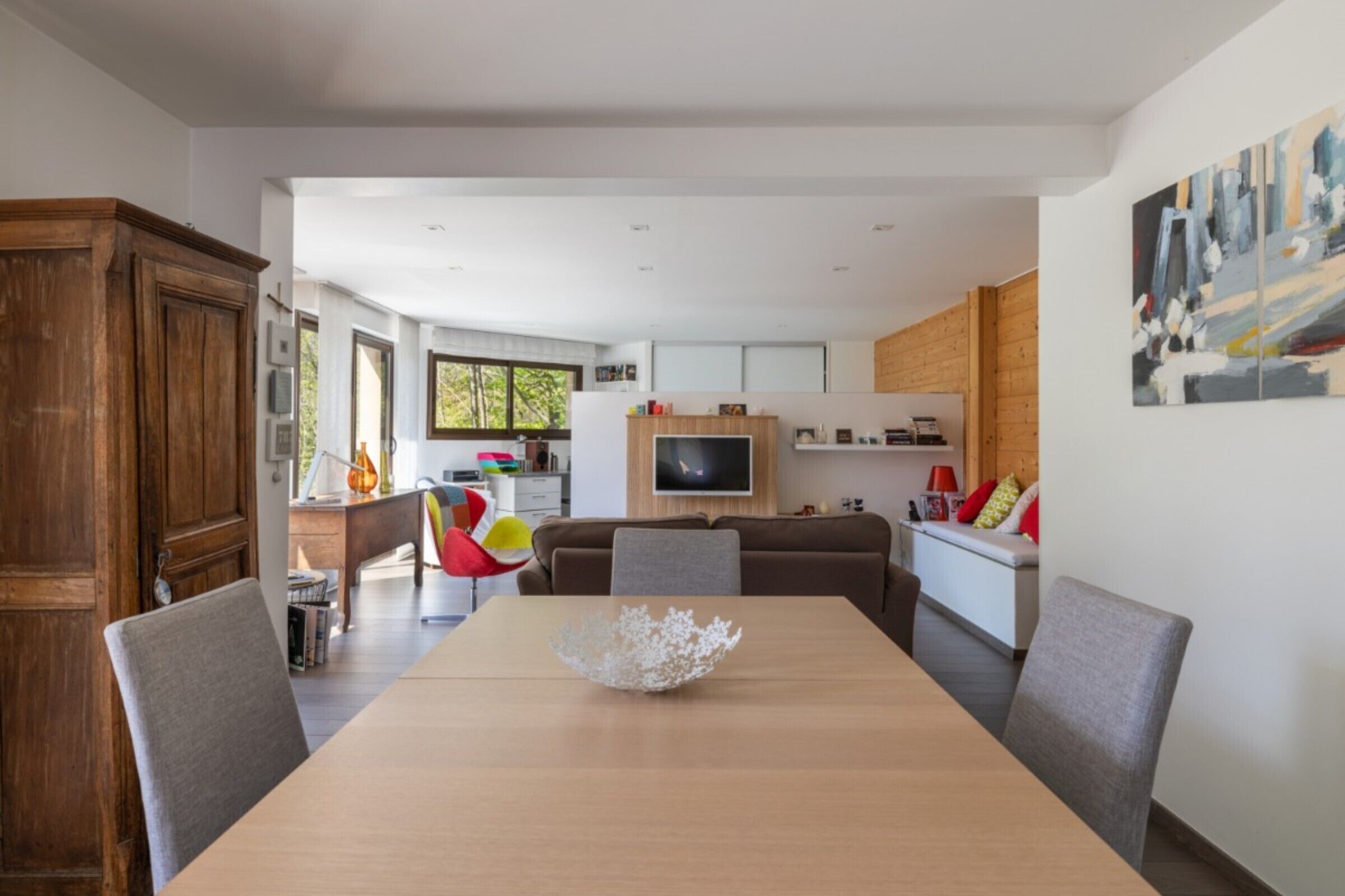 A modern dining area with a wooden table, chairs, and a decorative bowl centerpiece.