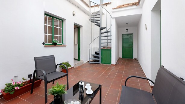 Ein kleiner, abgeschlossener Innenhof mit einer Wendeltreppe, einer Bank, einem Tisch mit Kaffeemaschine und Topfpflanzen.