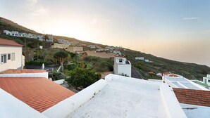 Eine Küstenstadt mit terrassenförmig angeordneten Häusern, blauem Himmel und Sonnenuntergang.