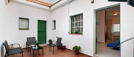 A room with a bed, a chair, a table, and a window.