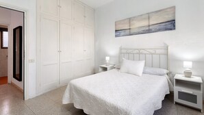 Ein Schlafzimmer mit einem Bett, Nachttischen, einem weißen Kleiderschrank und einem Bild an der Wand.