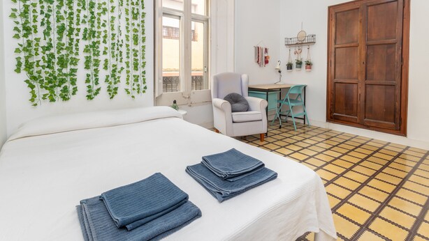 Ein Zimmer mit einem Bett, einem Schreibtisch, einem Stuhl, einem Fenster und einer Tür.