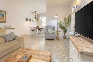 Un salon comprenant un canapé, une table basse, un téléviseur et un coin repas avec des chaises et une table.
