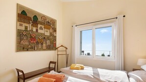 A hotel room with two beds, a painting on the wall, a window with a view, and a chair. - Vacation Home "Casa Inti" with Sea View, Private Garden & Wi-Fi (Tijarafe)