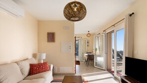 A living room with a sofa, a coffee table, a TV, and a dining area with a table and chairs. - Vacation Home "Casa Inti" with Sea View, Private Garden & Wi-Fi (Tijarafe)