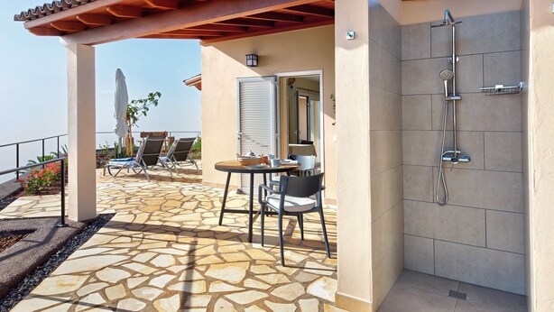 A covered outdoor area with a stone floor, a table with chairs, and a shower enclosure. - Vacation Home "Casa Inti" with Sea View, Private Garden & Wi-Fi (Tijarafe)
