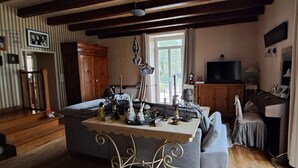 Ein gemütliches Wohnzimmer mit einer Couch, einem Tisch mit Dekoration, einem Fernseher und einem Holzschrank.
