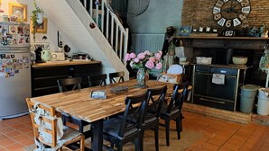 Eine Küche mit Holztisch, Stühlen, einem Kühlschrank und einer Treppe.