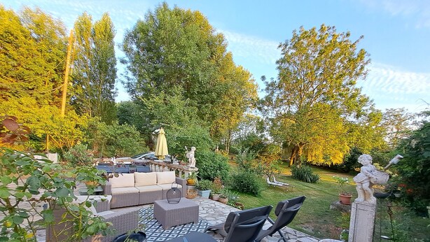 Eine Terrasse mit Gartenmöbeln, einer Statue und einem Garten.