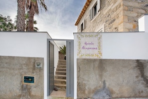 A building entrance with a sign reading 'Quinta Alcaparras,' a staircase, and a stone wall.