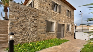 Un bâtiment en pierre avec un chemin pavé, un lampadaire et un parterre de fleurs.