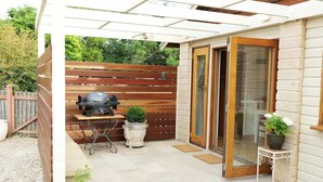A patio with a grill, potted plants, and a sliding glass door leading to a room. - Fair Linden's Morrow (Bowral)