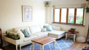 A living room with a white sofa, a wooden coffee table, a patterned rug, and a window with curtains. - Fair Linden's Morrow (Bowral)