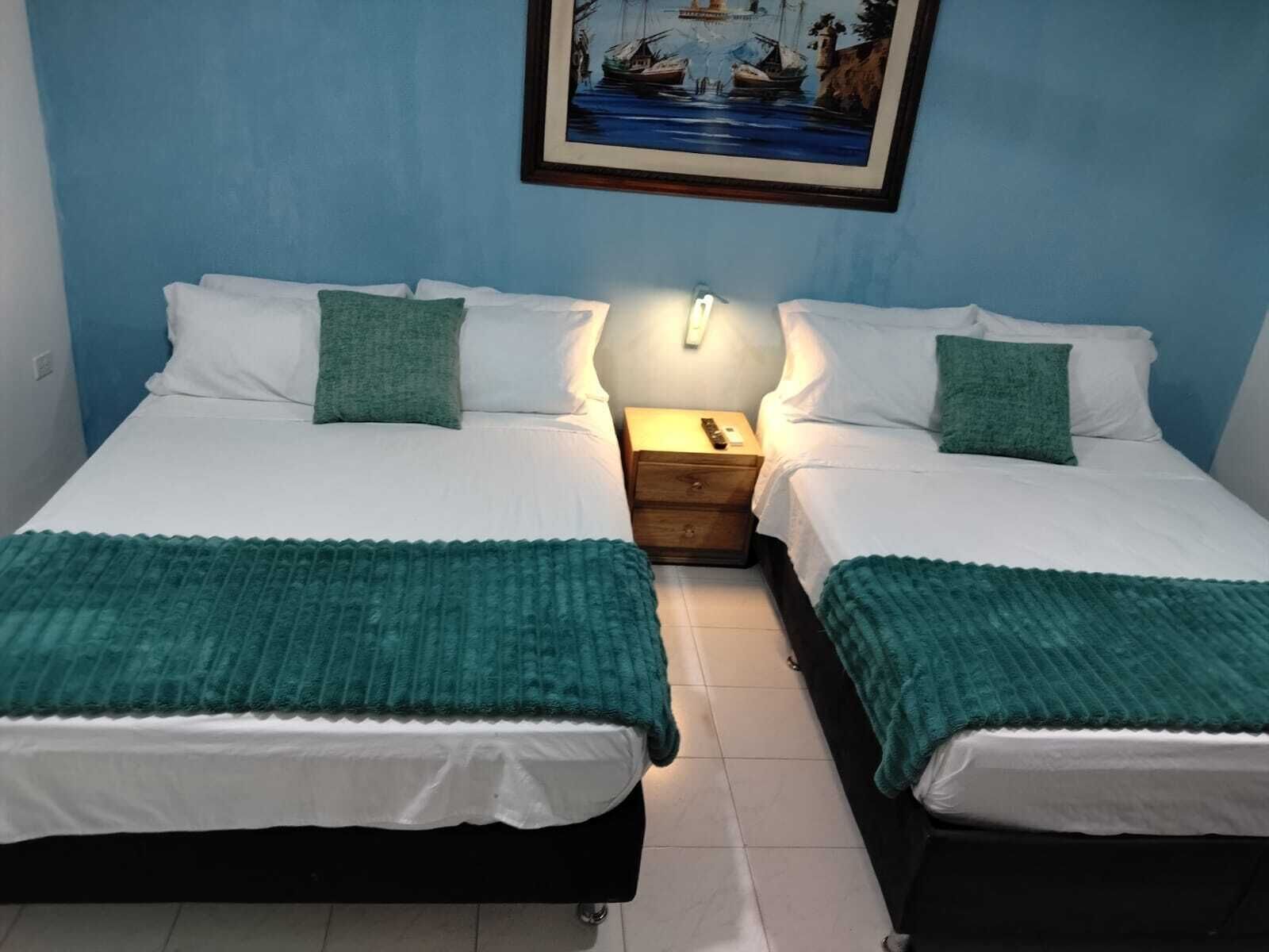 A double bed room with two bedside tables, a nightstand, and a framed picture on the wall.