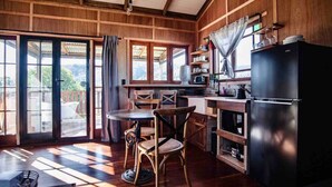 A wooden interior with a kitchen area, including a refrigerator, stove, and dining table with chairs. - Grey Gum Luxury Cottage & Highland Cows (Mount Pleasant)