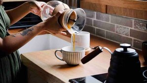 A person pouring a liquid from a container into a cup on a kitchen counter. - Grey Gum Luxury Cottage & Highland Cows (Mount Pleasant)