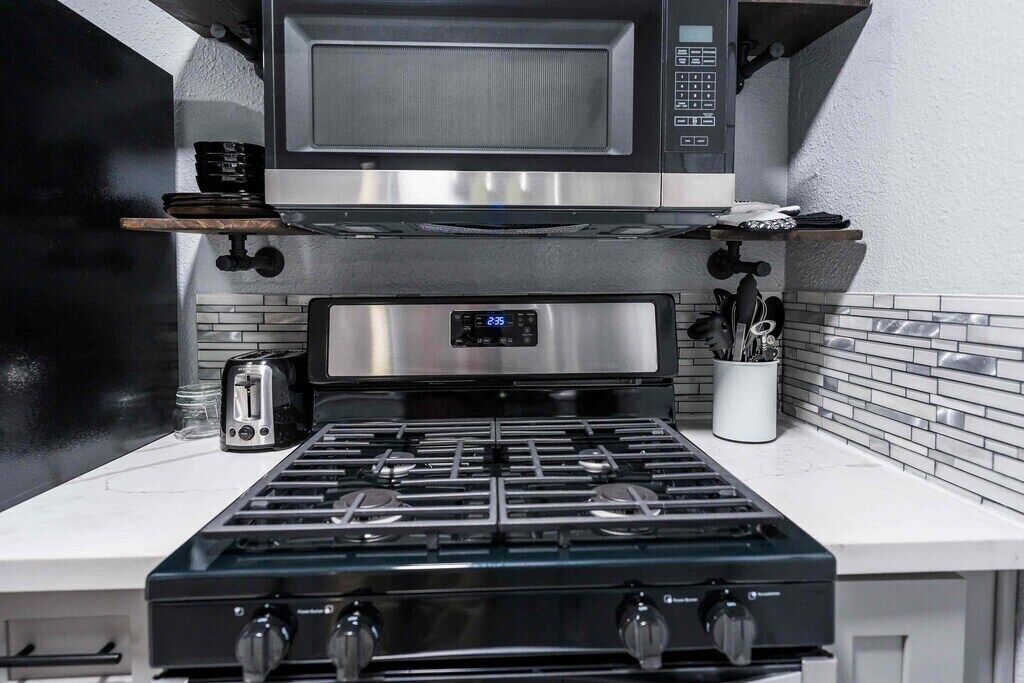 A modern kitchen with a stainless steel range hood, a microwave, and a gas stove.