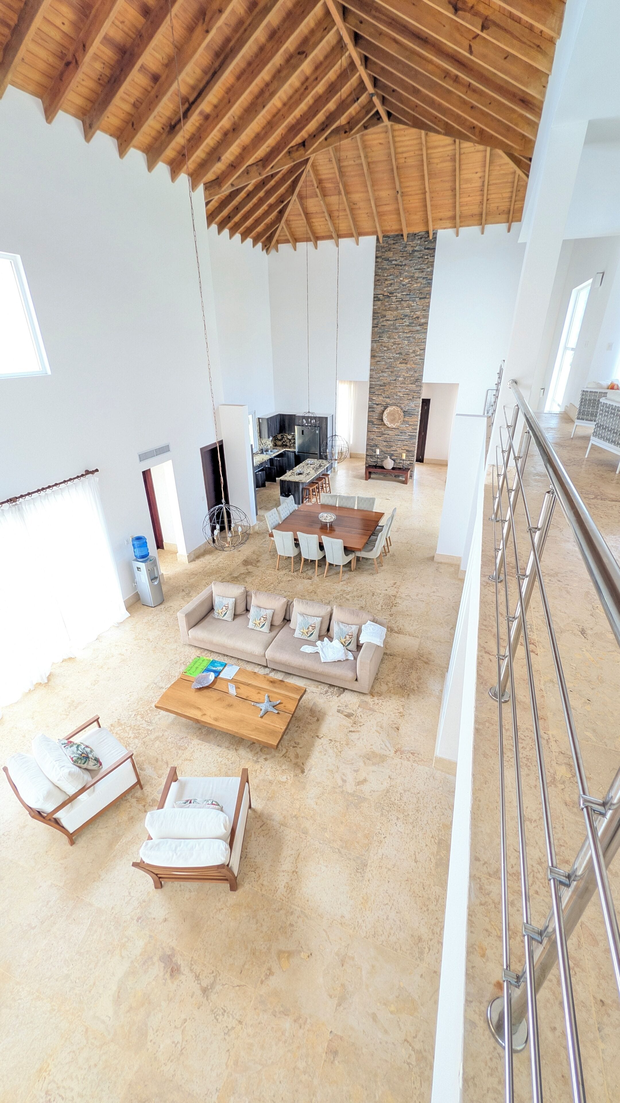 Un vaste espace de vie doté d’un haut plafond, d’un mur d’accent en pierre et d’un coin repas avec une grande table en bois.