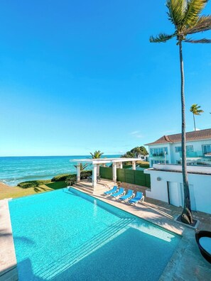 A poolside view with a clear blue sky, a pool, and a view of the ocean. - Peninsula Esmeralda Luxury Hotel & Villas (Puerto Plata)