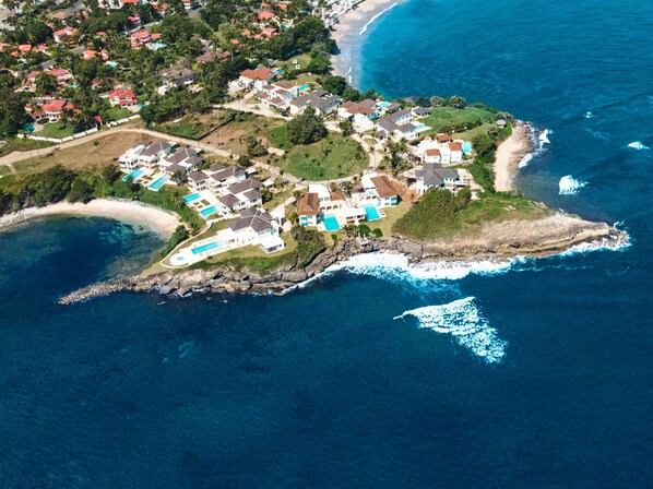 An aerial view of a coastal residential area with houses, a beach, and a rocky shoreline. - Peninsula Esmeralda Luxury Hotel & Villas (Puerto Plata)