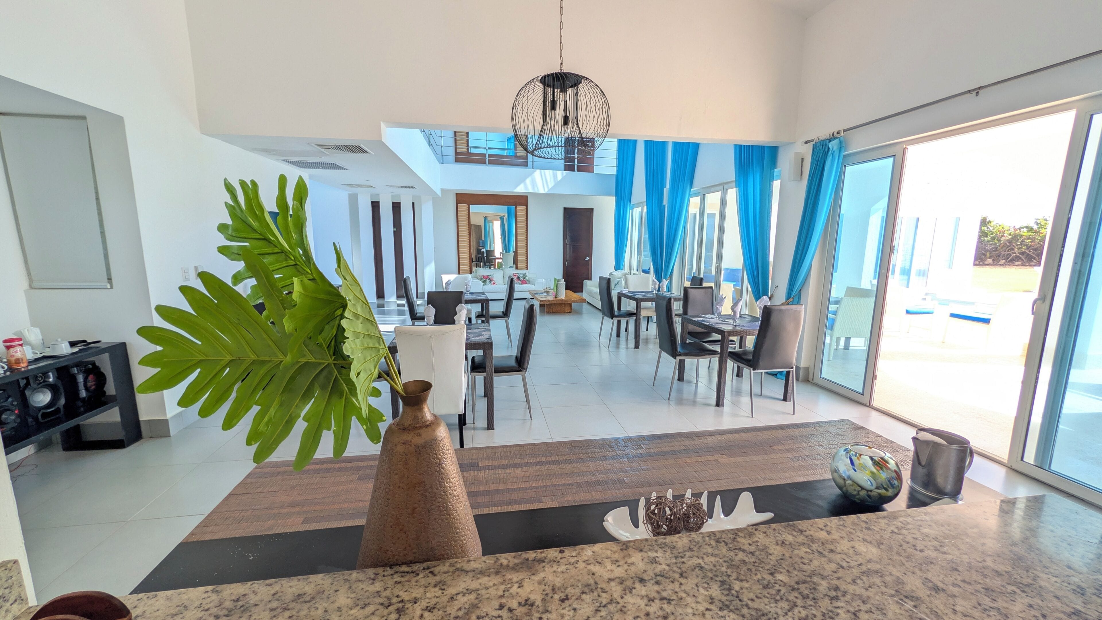 A modern interior with a dining area, kitchen, and large windows.
