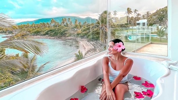 A person in a bathtub with a view of a tropical landscape. - Peninsula Esmeralda Luxury Hotel & Villas (Puerto Plata)