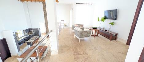 Amplia sala de estar con cocina, comedor y una escalera.